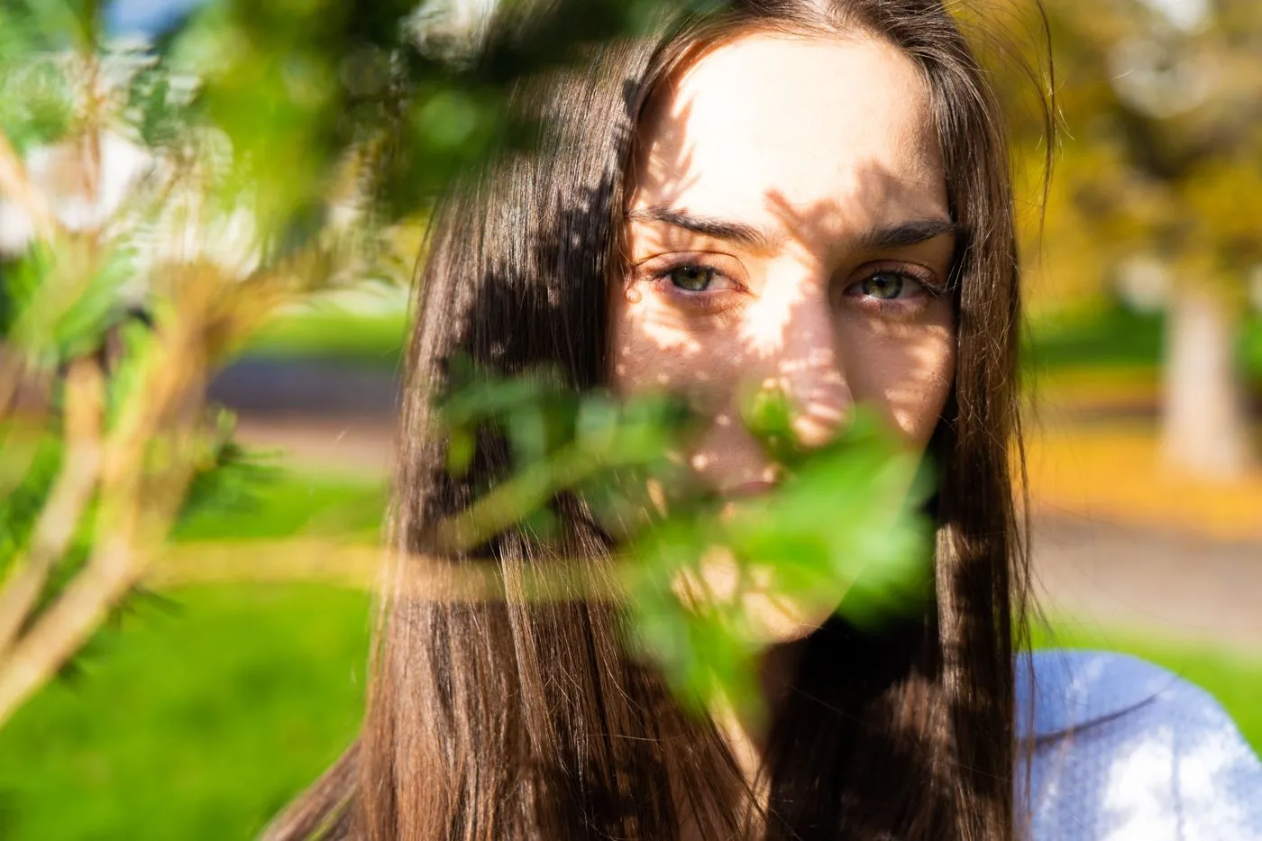 Creative arts: a portrait framed through leaves in dappled light